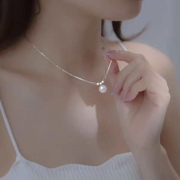 Close-up of woman touching Pearl Bead Necklace with purple nails