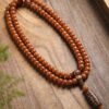 108-bead Buddhist mala, honey-colored prayer beads, natural seed necklace, meditation necklace, spiritual protection pendant, eye motif mala, handmade Buddhist jewelry, mindfulness accessory, Zen lifestyle gift, eco-friendly spiritual tool, unisex mala necklace, prayer beads for meditation, traditional mala design, earthy tone jewelry, calming energy beads, Buddhist ritual accessory, durable natural beads, minimalist spiritual wear, gift for yoga practitioners, authentic mala necklace.