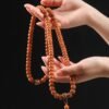 108-bead Buddhist mala, honey-colored prayer beads, natural seed necklace, meditation necklace, spiritual protection pendant, eye motif mala, handmade Buddhist jewelry, mindfulness accessory, Zen lifestyle gift, eco-friendly spiritual tool, unisex mala necklace, prayer beads for meditation, traditional mala design, earthy tone jewelry, calming energy beads, Buddhist ritual accessory, durable natural beads, minimalist spiritual wear, gift for yoga practitioners, authentic mala necklace.