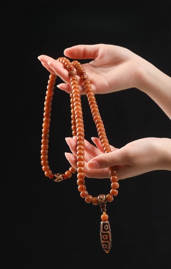 108-bead Buddhist mala, honey-colored prayer beads, natural seed necklace, meditation necklace, spiritual protection pendant, eye motif mala, handmade Buddhist jewelry, mindfulness accessory, Zen lifestyle gift, eco-friendly spiritual tool, unisex mala necklace, prayer beads for meditation, traditional mala design, earthy tone jewelry, calming energy beads, Buddhist ritual accessory, durable natural beads, minimalist spiritual wear, gift for yoga practitioners, authentic mala necklace.