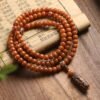 108-bead Buddhist mala, honey-colored prayer beads, natural seed necklace, meditation necklace, spiritual protection pendant, eye motif mala, handmade Buddhist jewelry, mindfulness accessory, Zen lifestyle gift, eco-friendly spiritual tool, unisex mala necklace, prayer beads for meditation, traditional mala design, earthy tone jewelry, calming energy beads, Buddhist ritual accessory, durable natural beads, minimalist spiritual wear, gift for yoga practitioners, authentic mala necklace.