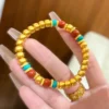 Hand Holding Gold Chinese Style Pumpkin Bead Bracelet with Red and Blue Beads