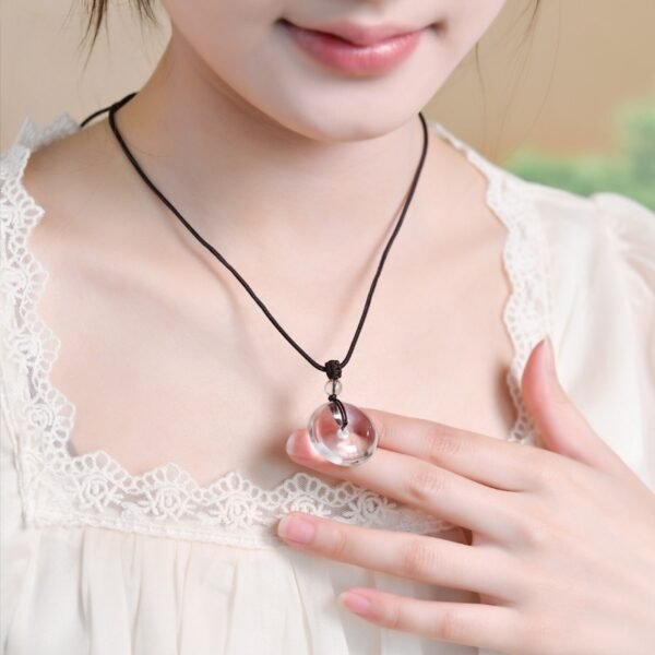 White crystal peace pendant, billion-year natural quartz, healing crystal jewelry, adjustable black cord necklace, minimalist spiritual accessory, energy balance pendant, artisan polished crystal, symbolic protection amulet, unisex crystal necklace, daily wear crystal jewelry, meaningful gift idea, Eastern culture inspired jewelry, Zen style pendant, holistic wellness accessory, natural quartz pendant, sleek crystal design, meditation jewelry, eco-friendly mineral gift, high-gloss finish crystal, timeless elegance jewelry.