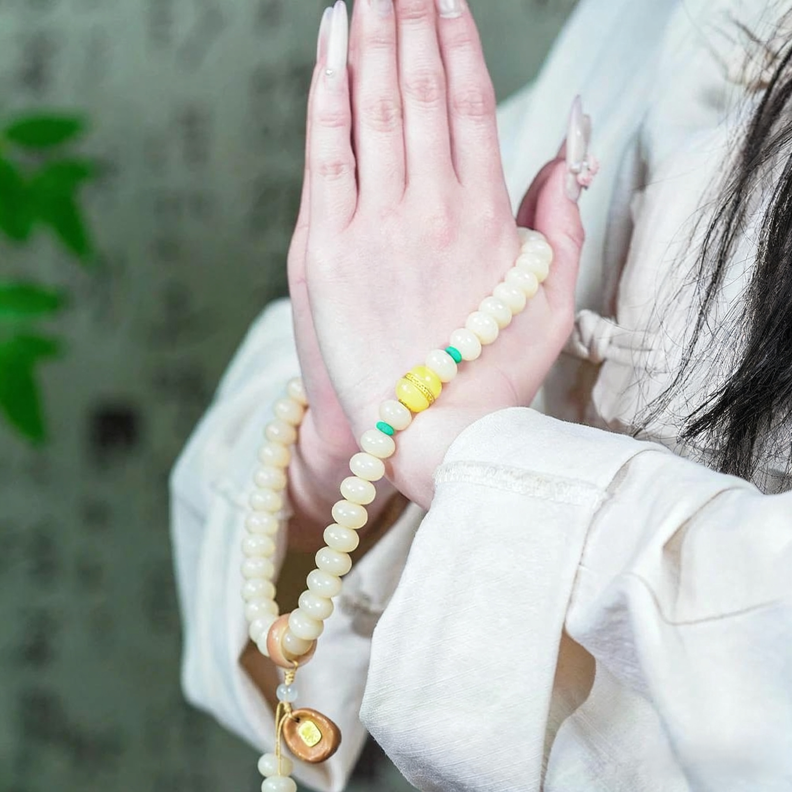 Woman's Hands in Prayer with White Jade Bodhi Mala and Traditional Sleeve