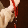 Two Hands Holding Red 108-Bead Bodhi Mala with Metal Accents