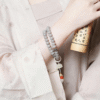 Close-up of Hand Holding Smoky Grey Bodhi Bracelet with Red Nails