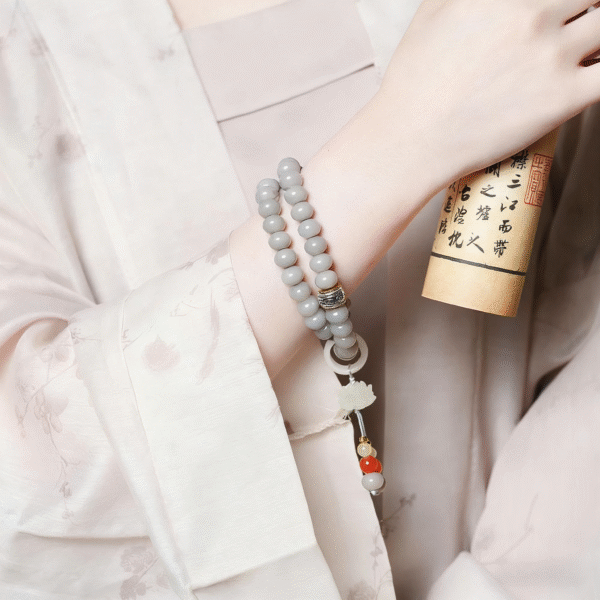 Close-up of Hand Holding Smoky Grey Bodhi Bracelet with Red Nails