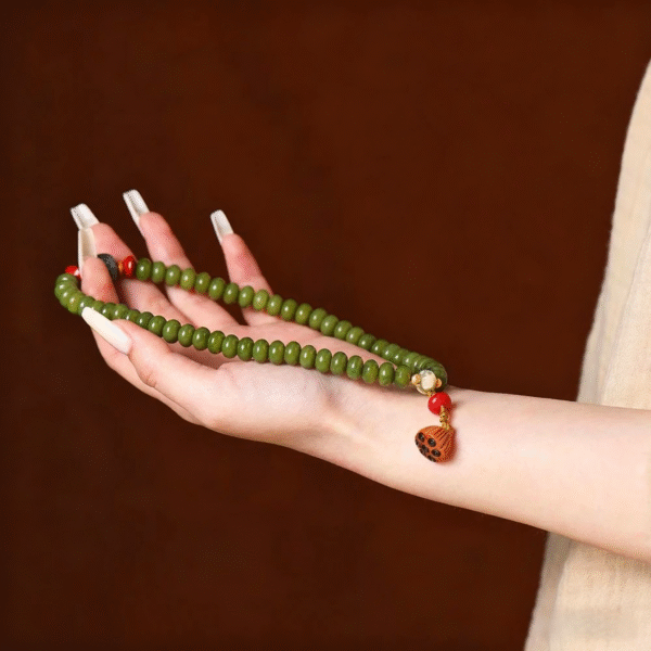 Hand Holding Green Bodhi Bead Bracelet with Lotus Pod Charm