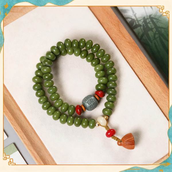 Green Bodhi Mala Bracelet with Red Accents on Wooden Tray